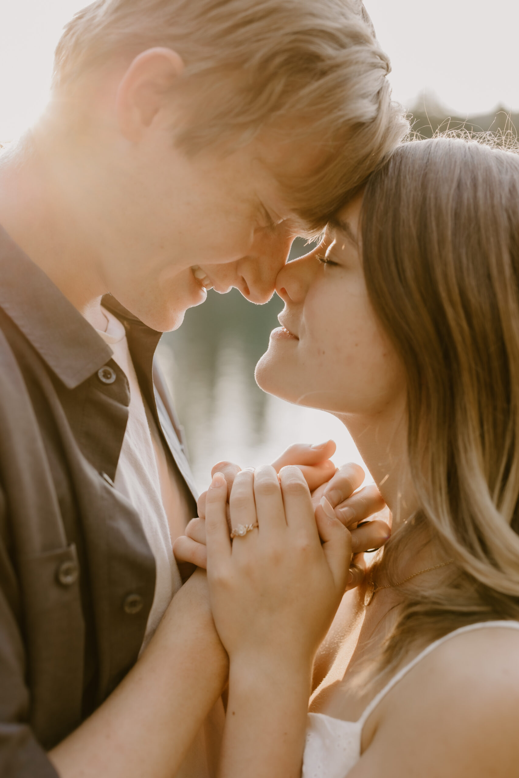 a couple holding hands and looking into each others eyes with their foreheads pressed together