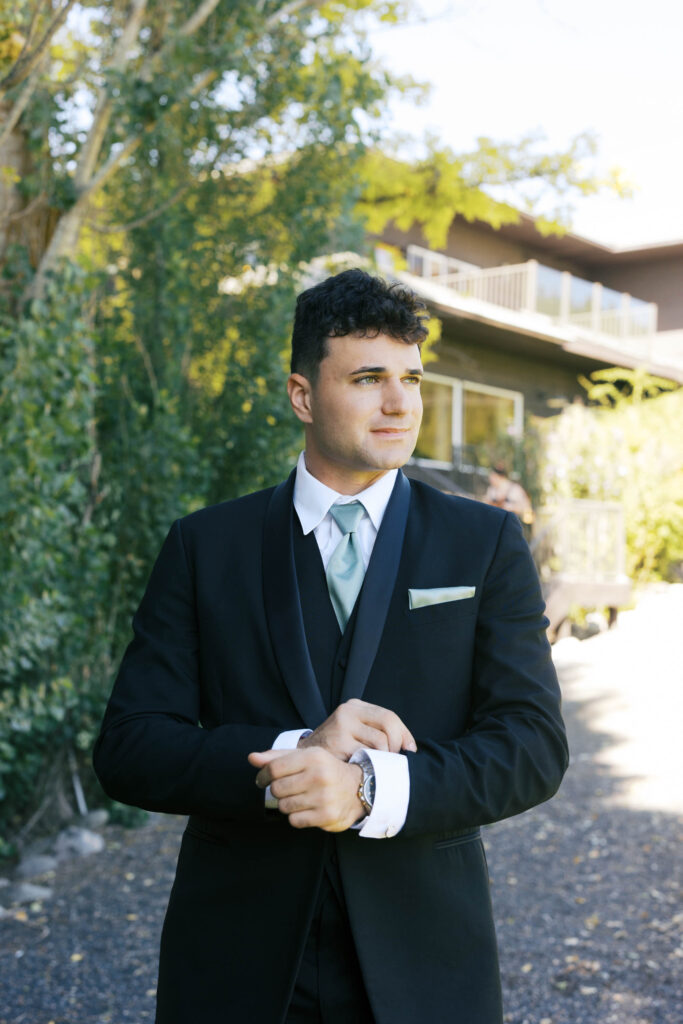 groom looking off to the distance while holding his suits cuffs 
