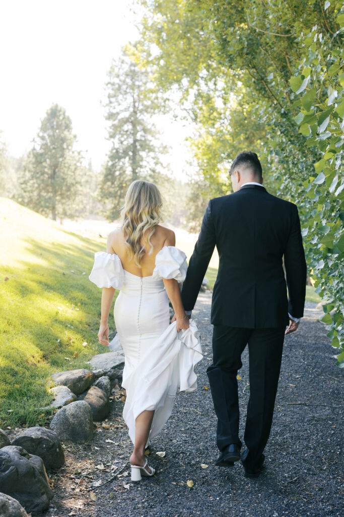 bride and groom walking away with the groom holding the brides dress