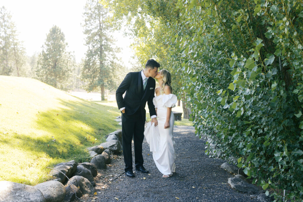 bride and groom kissing while the groom holds the brides dress. 