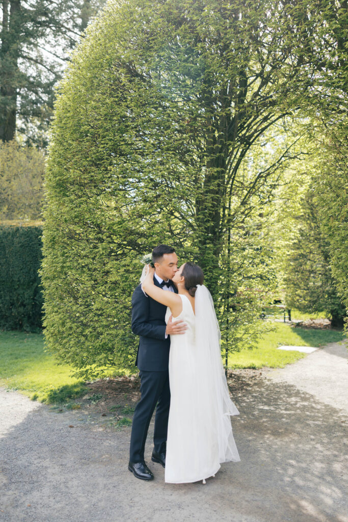 Bride and groom kissing in lush garden during their wedding first look