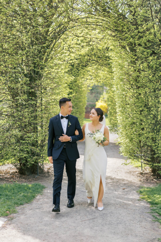 Bride and groom walking arm-in-arm through garden path at Manito Park