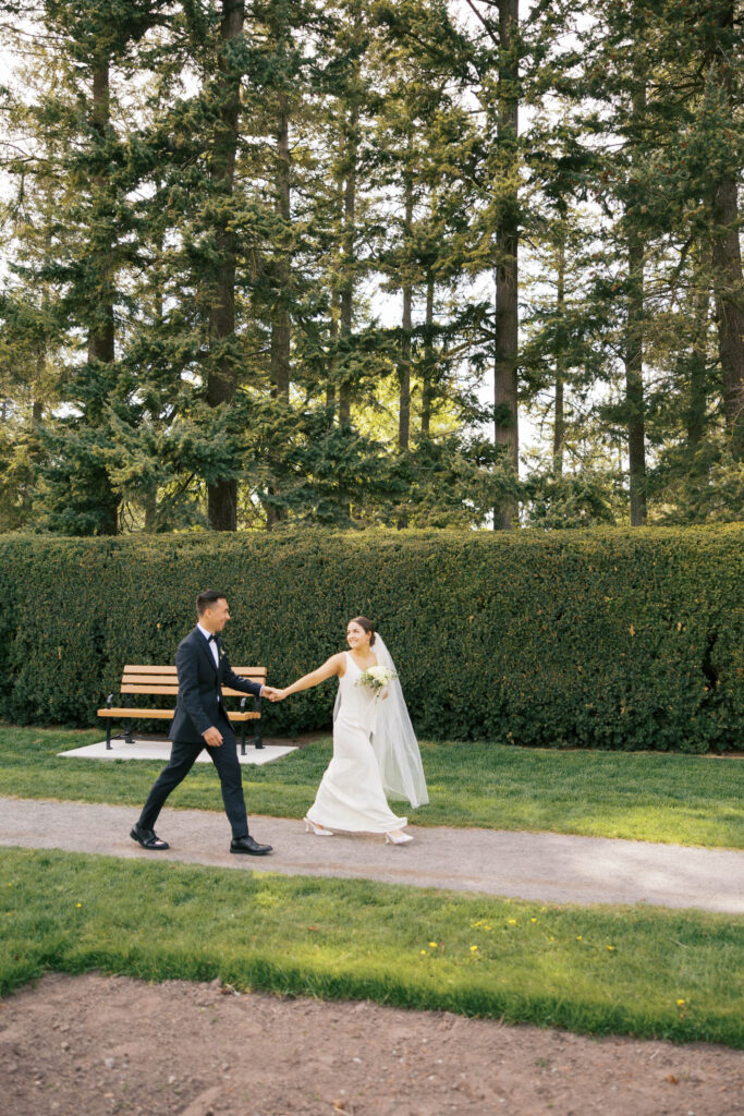 Newlyweds walking together near manicured hedge garden at Manito Park in Spokane.