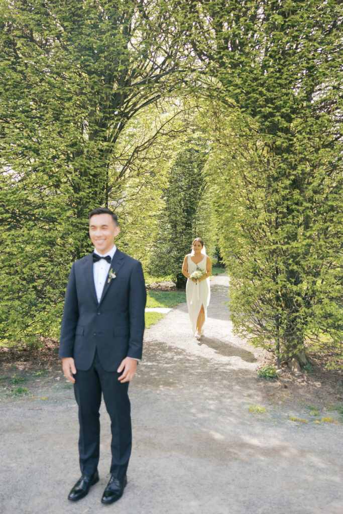 Bride walking toward groom during their first look at Manito Park in Spokane, WA