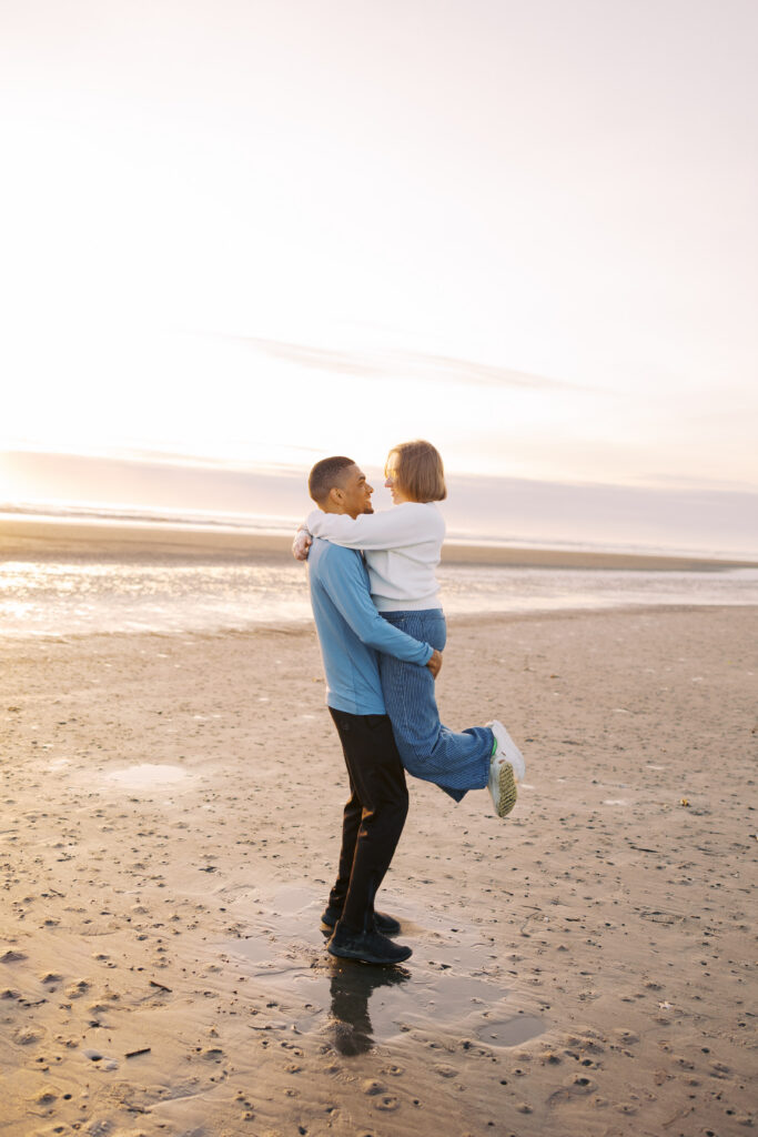 A'lon lifting Julia at sunset during their Pacific Northwest beach engagement session