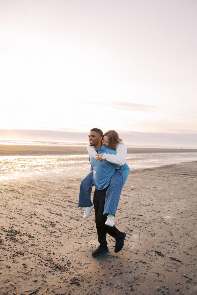 A'lon giving Julia a piggyback ride along the shoreline at sunset
