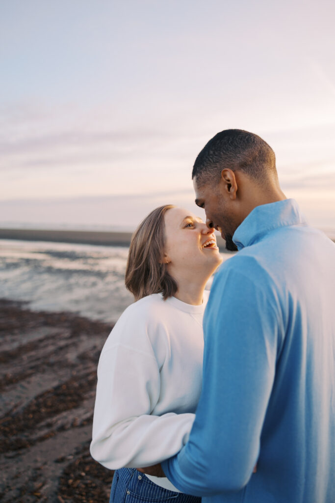 Julia and A'lon laughing close together during their Seabrook engagement session at Pacific Glen
